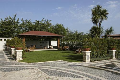 un jardín con cenador, sillas y árboles en Hotel Lemi en Benevento