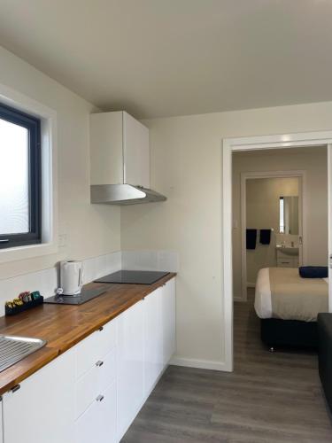 een keuken met witte kasten en een bed in een kamer bij Gum Tree Caravan Park in Port Fairy