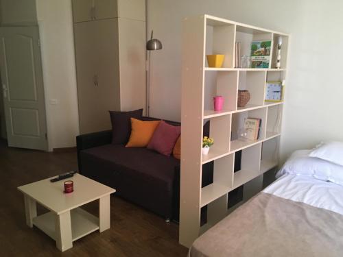 a living room with a couch and a book shelf at Studio Cosy MM in Tbilisi City