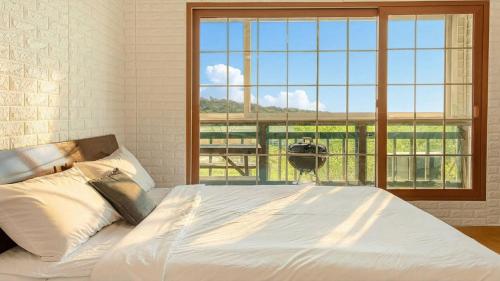een slaapkamer met een bed en een groot raam bij Ganghwa Ara Pension in Incheon