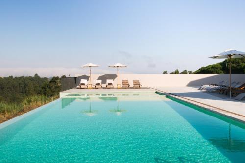 a swimming pool with chairs and umbrellas on top of it at Vale d'Azenha Hotel Rural & Residences in Alcobaça