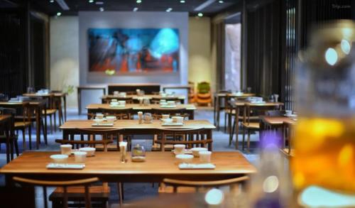 een restaurant met houten tafels en stoelen en een groot scherm bij Tsingpu Tulou Retreat 青普文化行馆 南靖土楼店 in Nanjing