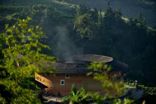 a house with a roof in the middle of a mountain at Tsingpu Tulou Retreat 青普文化行馆 南靖土楼店 in Futian