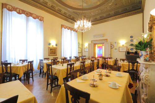 a restaurant with yellow tables and chairs and a chandelier at Hotel Villa Liana in Florence