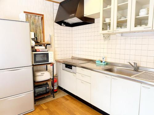 een keuken met witte kasten en een spoelbak bij Runesu Karuizawa - Vacation STAY 78428v in Tsumagoi