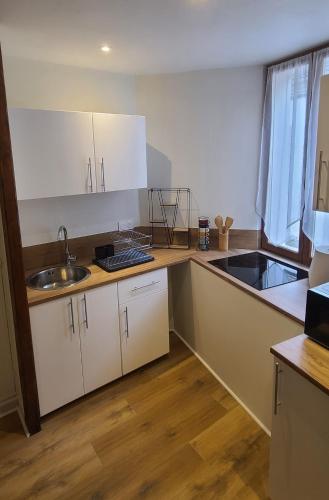 a kitchen with white cabinets and a sink at Au deuxième in Nogent-sur-Seine