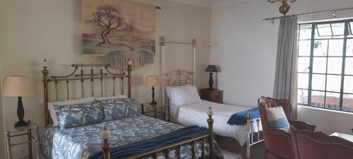 een slaapkamer met twee bedden en een stoel en een raam bij Rondebosch Gardens in Humansdorp
