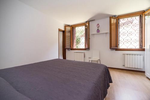 a bedroom with a bed and two windows at Venice Biennale Garibaldi in Venice