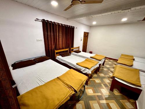 ein Zimmer mit vier Betten und gelben Laken in der Unterkunft Siddhi Farm Kolad in Kolad