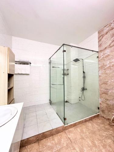 a glass shower in a bathroom with a sink at OThuy's House in Hue in Hue