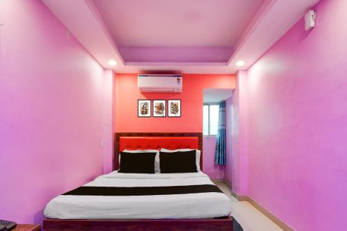 een slaapkamer met roze muren en een groot bed bij Hotel O Golden Star in Ballygunge