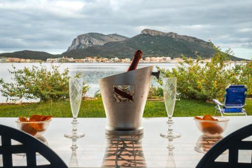 een tafel met wijnglazen en een fles erop bij Appartamento Baia Caddinas fronte mare in Golfo Aranci