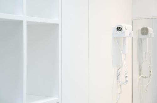 a bathroom with a shower with a phone on the wall at Bedd Hostel in Bangkok