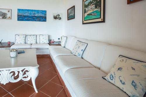 een woonkamer met een witte bank en een tafel bij Appartamento Baia Caddinas fronte mare in Golfo Aranci