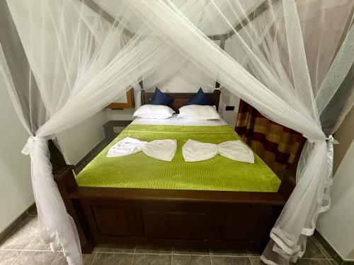 una camera con letto a baldacchino con lenzuola e cuscini verdi di Lagoonlike Hiriketiya a Dikwella