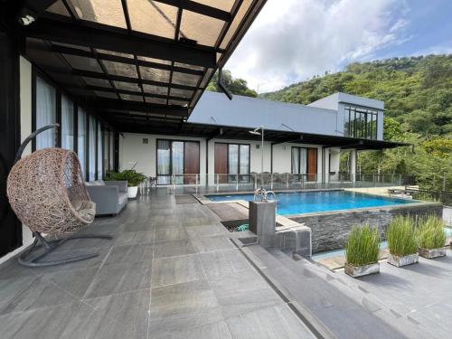 eine Außenterrasse mit einem Pool und einem Haus in der Unterkunft Anemos Resort By Tamastu in Pasirpogor