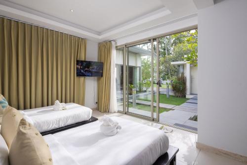 twee bedden in een kamer met een groot raam bij La Lagune in Laem Set Beach
