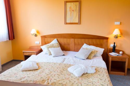 ein Schlafzimmer mit einem Bett mit zwei Kissen darauf in der Unterkunft Karos Gold 813 Wellness Apartman in Zalakaros