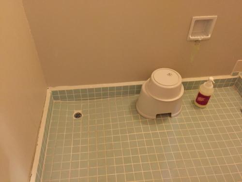 a bathroom with a tiled floor with a trash can at Hotel Kadoman in Aso