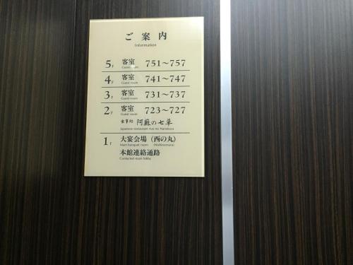 a sign on the side of a door with writing on it at Hotel Kadoman in Aso