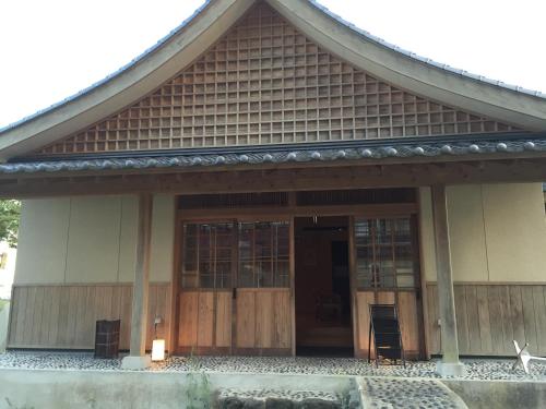 a house with a large wooden door and a porch at Hotel Kadoman in Aso