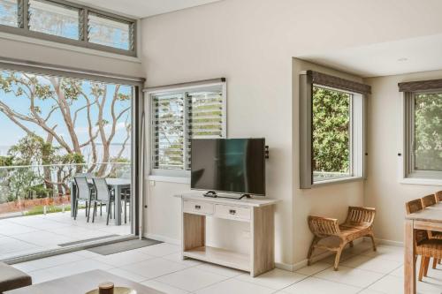 a living room with a television and a table with chairs at Entice at Hyams - pet-friendly beachfront home in Hyams Beach