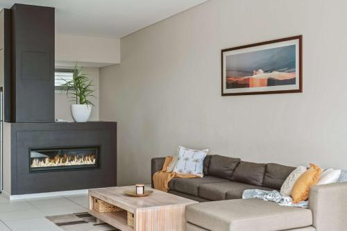 a living room with a couch and a fireplace at Entice at Hyams - pet-friendly beachfront home in Hyams Beach