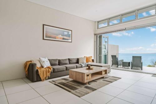 a living room with a couch and a coffee table at Entice at Hyams - pet-friendly beachfront home in Hyams Beach