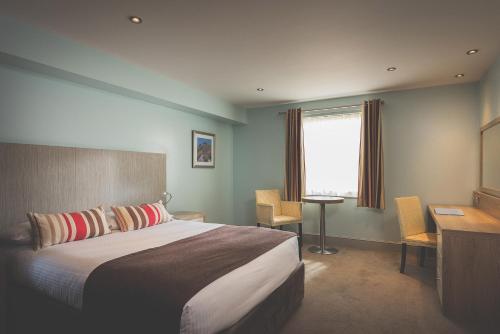 a bedroom with a bed and a desk and a window at County Arms in Truro