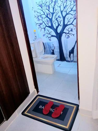 a bathroom with a toilet and a door with red shoes at Diani Beach rentals - 201 Studio Apartment in Diani Beach