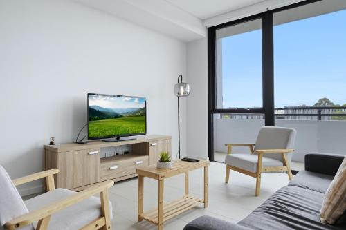 a living room with a flat screen tv on a wooden cabinet at Luxury 2BR Stay near Olympic Park Parramatta FREE Parking in Sydney