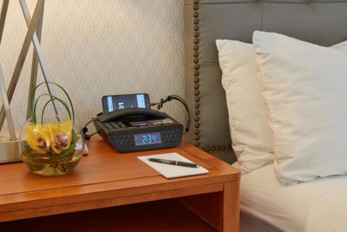 a table with a clock and a telephone on a bed at The Kensington Hotel in Ann Arbor