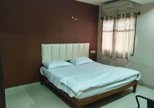 a bedroom with a large bed with white sheets and a window at Geetha Residency in Anantapur
