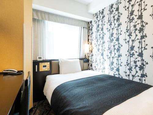 a hotel room with a bed and a window at APA Hotel Osaka Kadomashi Ekimae in Kadoma