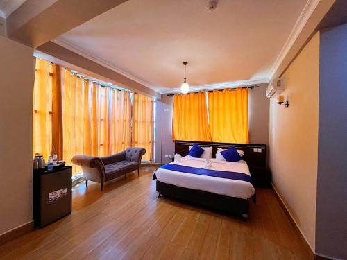 a bedroom with a bed and a chair and windows at Rejis Hotel in Dodoma