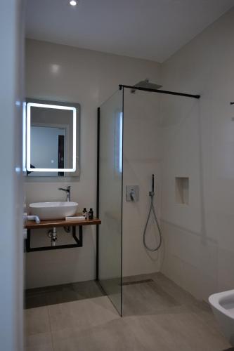 een badkamer met een wastafel, een douche en een bad bij The Blue Wave Hotel in Himare