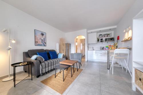 a living room with a couch and a table at Carpe Diem Apartment - Pool view By Lanzarote Vacation Homes in Puerto del Carmen
