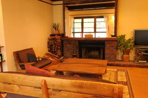 a living room with a table and a fireplace at Pension Syo in Hakuba