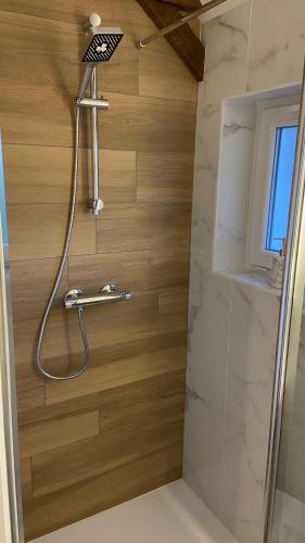 a shower in a bathroom with a wooden wall at Charmante maison in Pleumeleuc