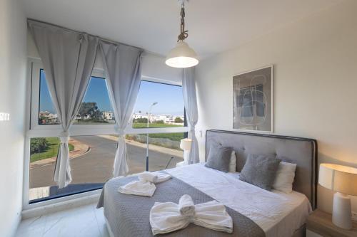a bedroom with a bed with a large window at Mythical Blue Villas in Protaras