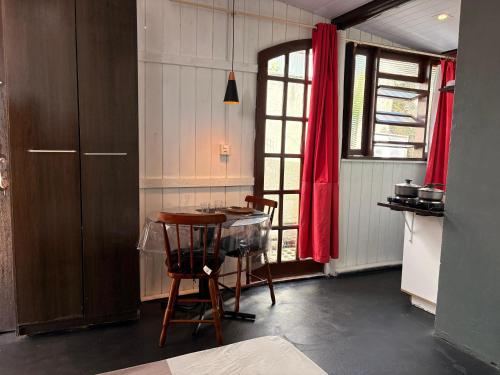 een keuken met een tafel en een rood gordijn bij Chalé Black no Sul da Ilha in Florianópolis