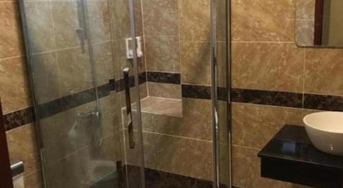een glazen douchedeur in een badkamer met een wastafel bij Phuong Ly Ly in Ho Chi Minh-stad