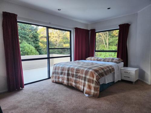 a bedroom with a bed and two large windows at Entire home in Birkenhead in Auckland