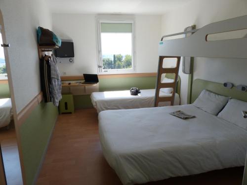 a hotel room with two beds and a desk at Ibis Budget Marseille Valentine in Marseille