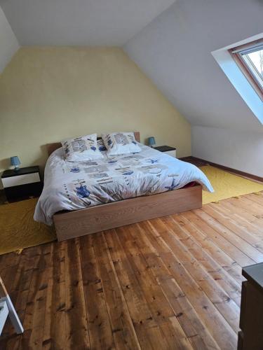 een slaapkamer met een bed en een houten vloer bij Maison de vacances in Plougasnou