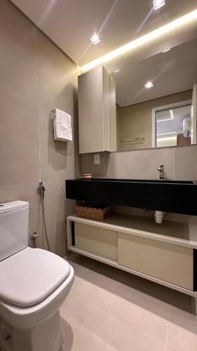 a bathroom with a white toilet and a mirror at High Standard Two Bedroom Apartment Private Pool Frances Beach Garden 209 in Marechal Deodoro