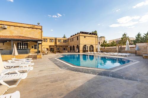 een zwembad met witte ligstoelen en een gebouw bij Ciner Hotel in Goreme