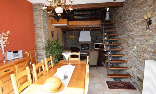 a dining room with a table and a spiral staircase at La Grange in Rochehaut