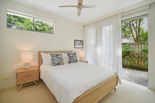 een witte slaapkamer met een bed en een raam bij Coastal Chic with Heated Pool Quiet Location in Sunshine Beach