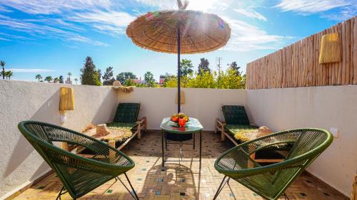 a patio with two chairs and a table with an umbrella at Riad Alaya, Rooftop Pool & Koutoubia View in Marrakesh